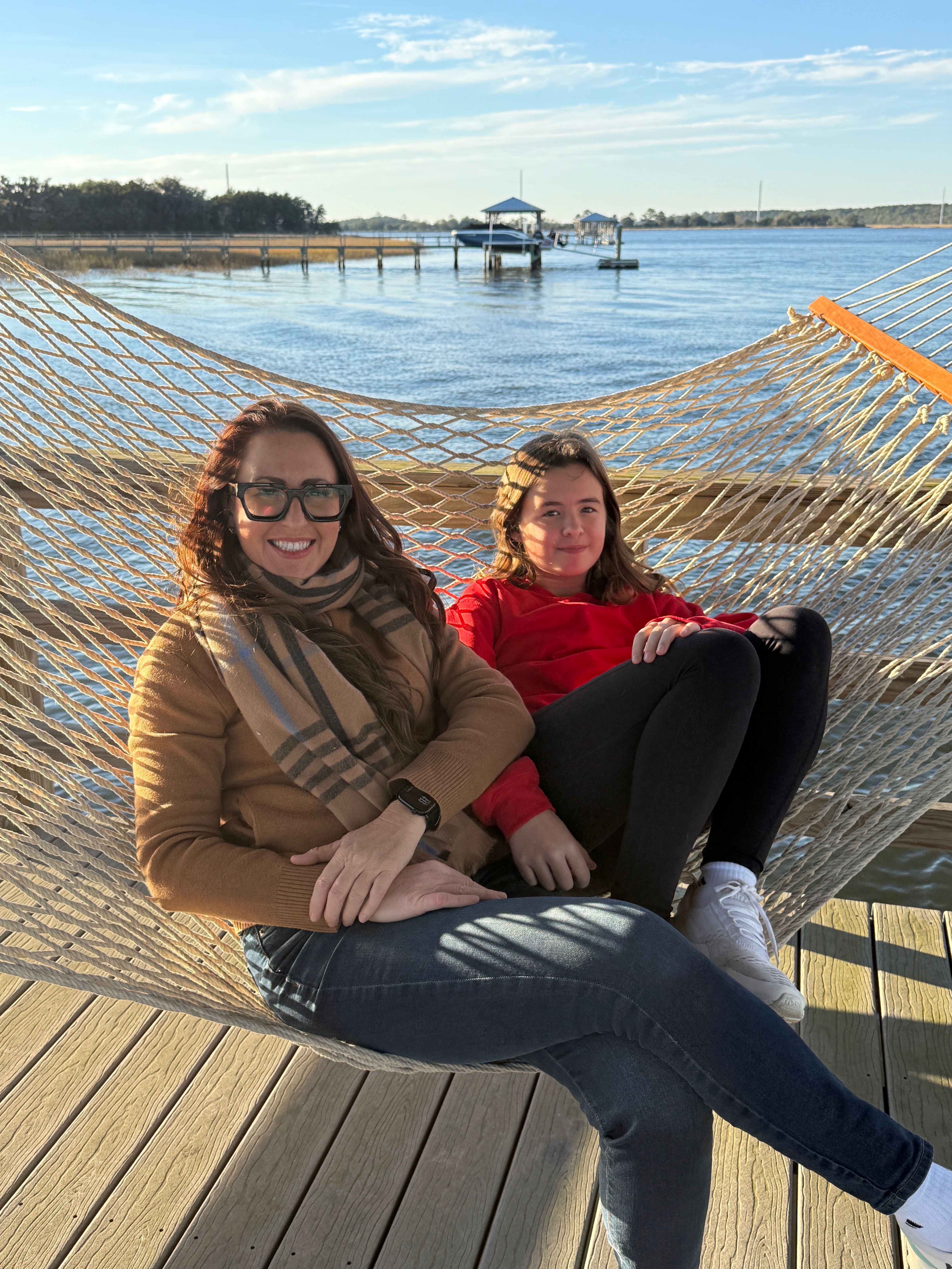 Kate Baldwin and her daughter Olivia sitting together in a hammock overlooking the water