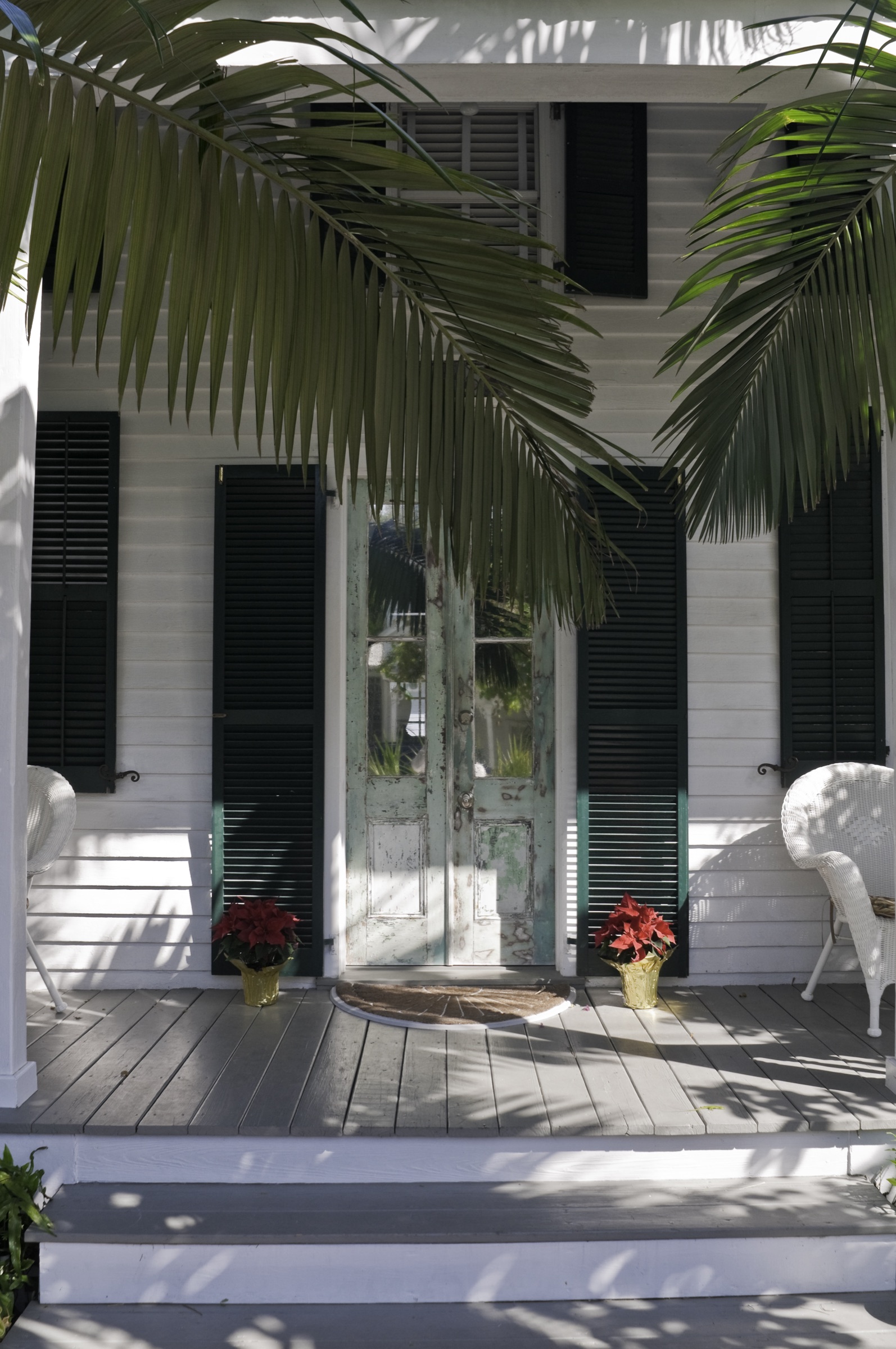 Historic Key West home entrance with weathered aqua doors and dark shutters