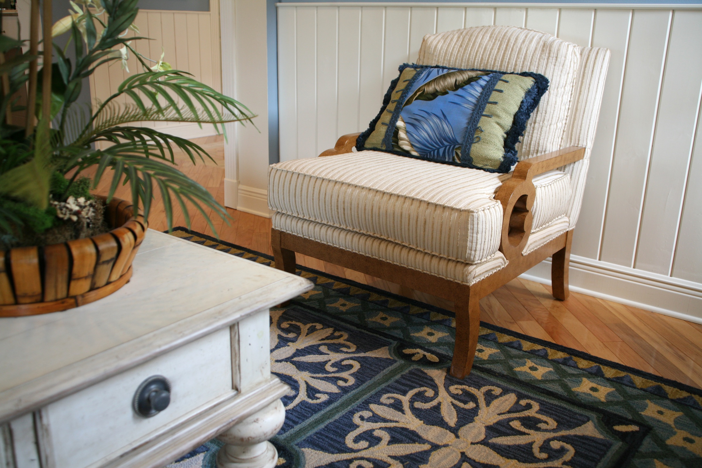 Coastal home interior detail with an upholstered chair and palm-print pillow